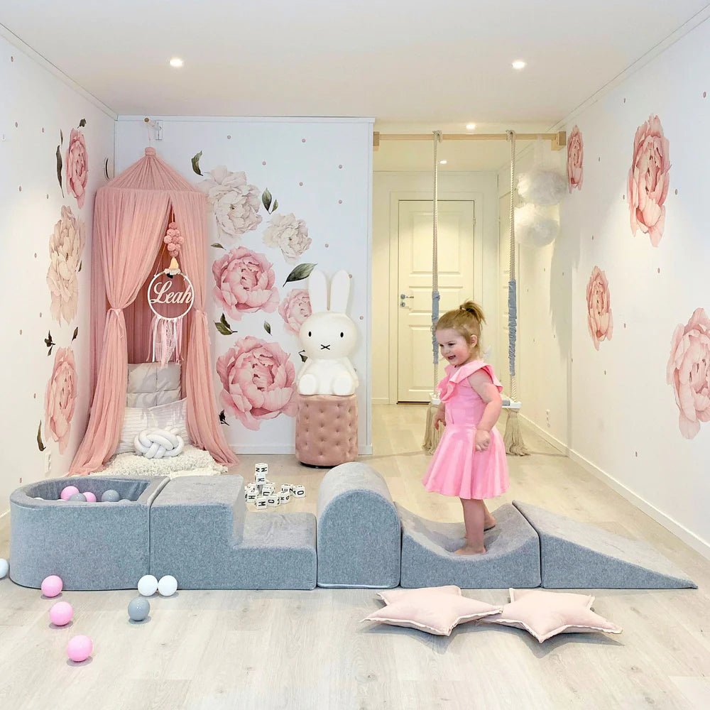 Children's room with pink floral wall decor, a bed with pink canopy, and a child in a pink dress.